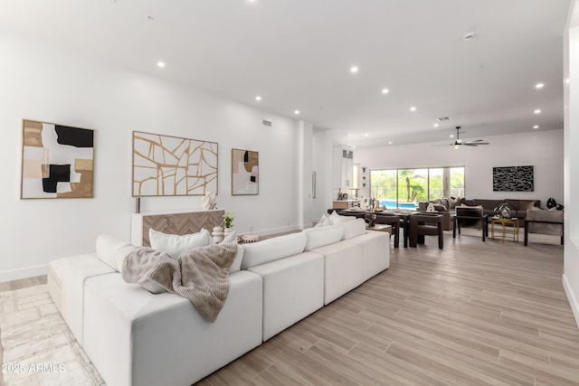 living area featuring recessed lighting, ceiling fan, light wood finished floors, and baseboards