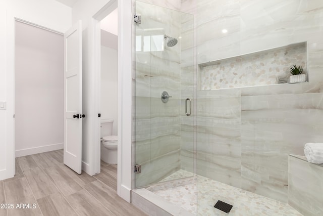 full bathroom featuring a stall shower, toilet, wood finished floors, and baseboards