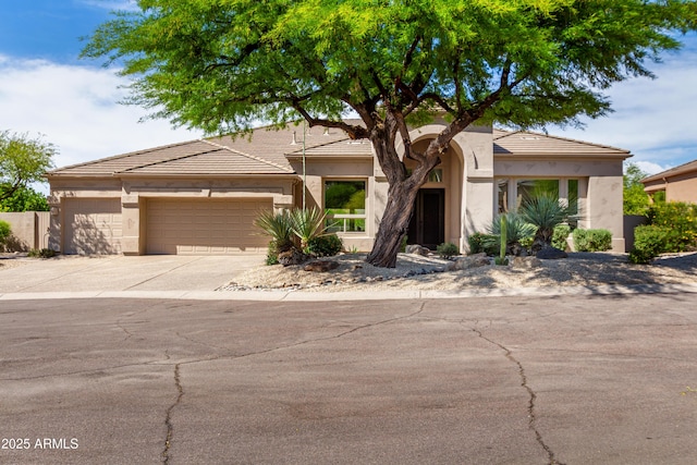 view of front of home featuring an attached garage, concrete driveway, a tile roof, and stucco siding
