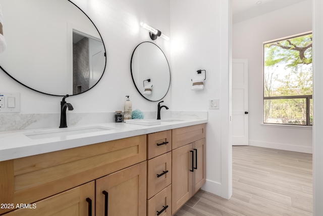 bathroom with double vanity, plenty of natural light, wood finished floors, and baseboards