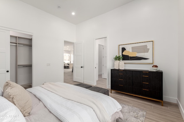 bedroom with light wood-type flooring, baseboards, a closet, and recessed lighting