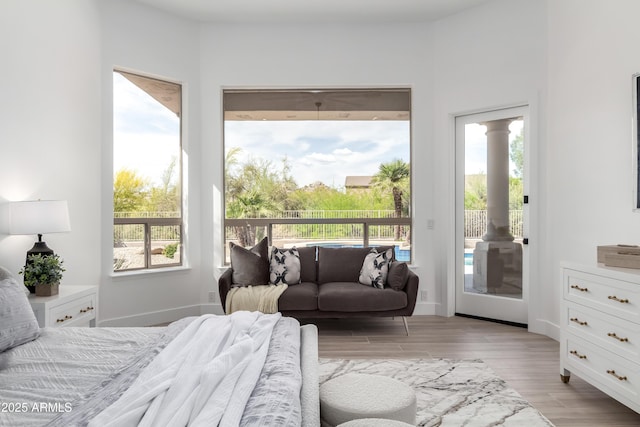 bedroom with access to outside, light wood finished floors, multiple windows, and decorative columns