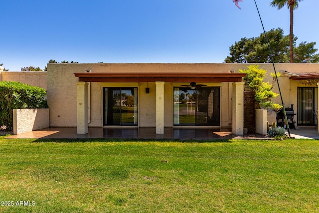 back of property with a patio area, stucco siding, and a lawn