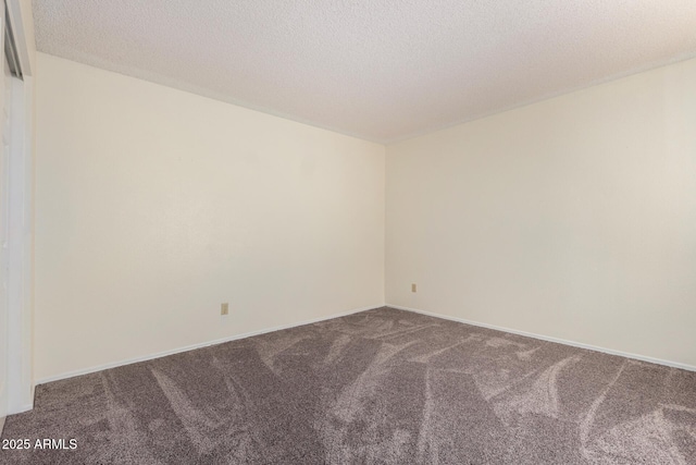 carpeted empty room featuring a textured ceiling and baseboards