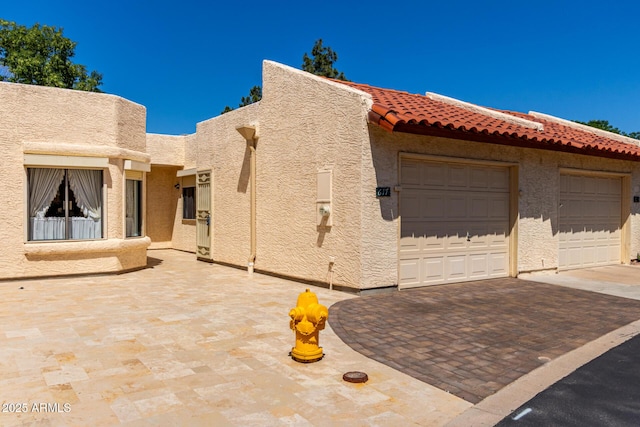 view of property exterior with an attached garage, driveway, stucco siding, and a tile roof