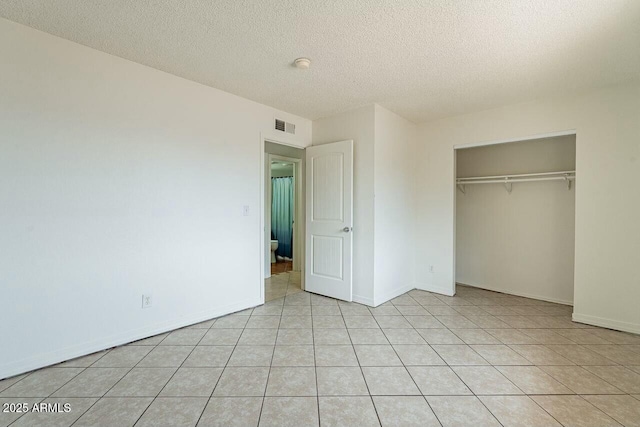 unfurnished bedroom featuring visible vents, baseboards, light tile patterned floors, a closet, and a textured ceiling