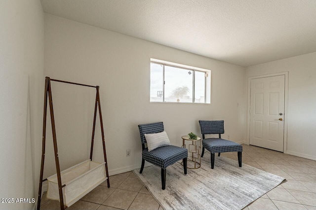 sitting room with light tile patterned flooring, baseboards, and a textured ceiling