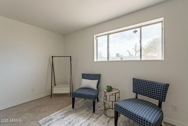 sitting room with light tile patterned floors, baseboards, and a textured ceiling