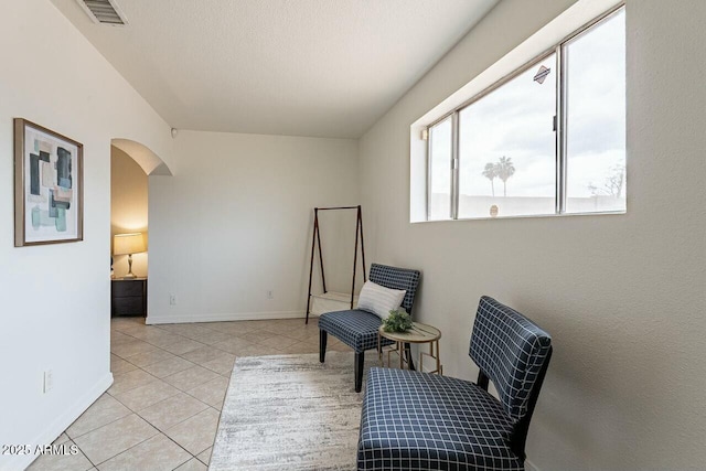 sitting room featuring light tile patterned floors, arched walkways, visible vents, and baseboards