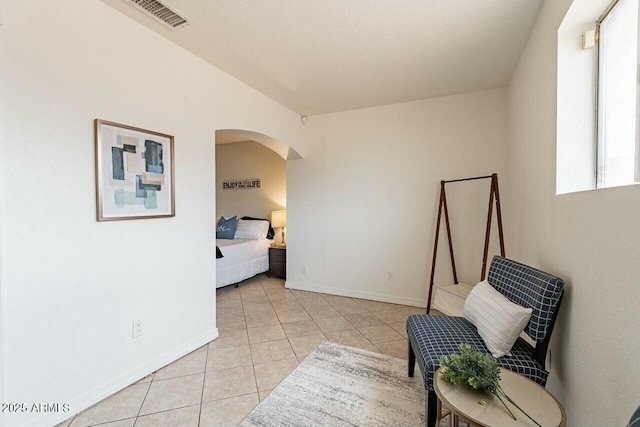 bedroom with light tile patterned flooring, visible vents, arched walkways, and baseboards