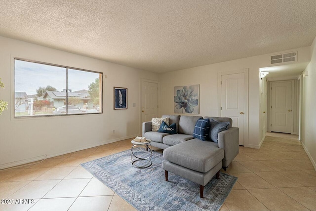 living area featuring light tile patterned floors, visible vents, and a textured ceiling