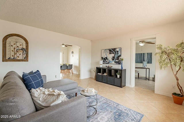 living room featuring light tile patterned floors, a textured ceiling, and ceiling fan