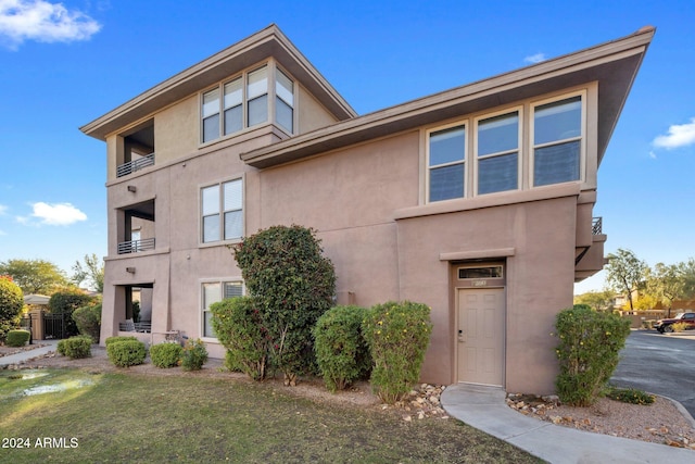 view of front of home featuring a balcony and a front lawn