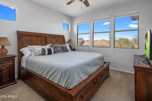 bedroom with multiple windows, ceiling fan, and light colored carpet