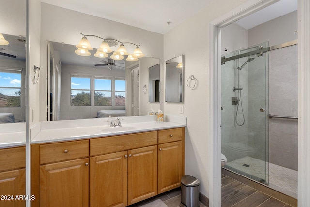 bathroom with ceiling fan, toilet, a shower with door, and vanity