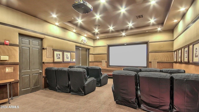 home theater room featuring a tray ceiling and light colored carpet