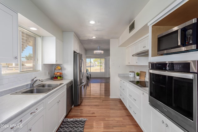 kitchen with appliances with stainless steel finishes, light hardwood / wood-style floors, white cabinetry, and sink