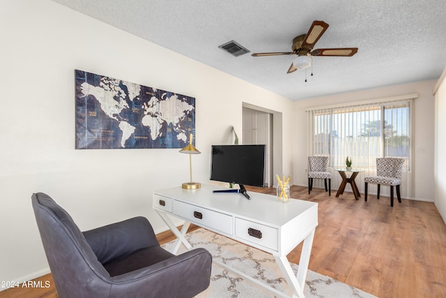 living room featuring ceiling fan, wood-type flooring, and a textured ceiling