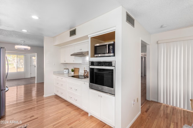 kitchen with white cabinetry, tasteful backsplash, light hardwood / wood-style flooring, a textured ceiling, and appliances with stainless steel finishes