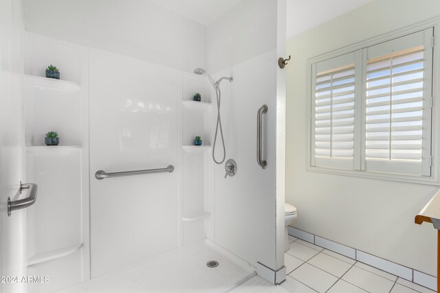 bathroom with tile patterned floors, toilet, and a shower