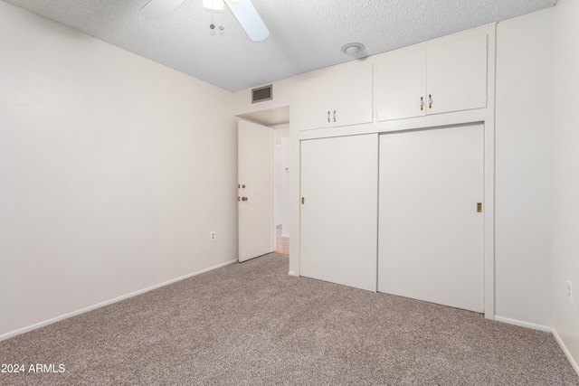 unfurnished bedroom with ceiling fan, light colored carpet, a textured ceiling, and a closet