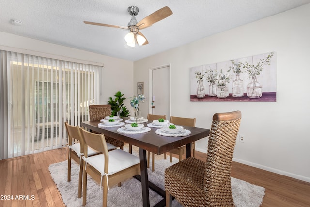 dining space with hardwood / wood-style floors, ceiling fan, and a textured ceiling