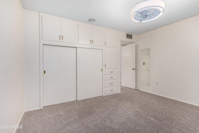 unfurnished bedroom with carpet, a textured ceiling, and a closet