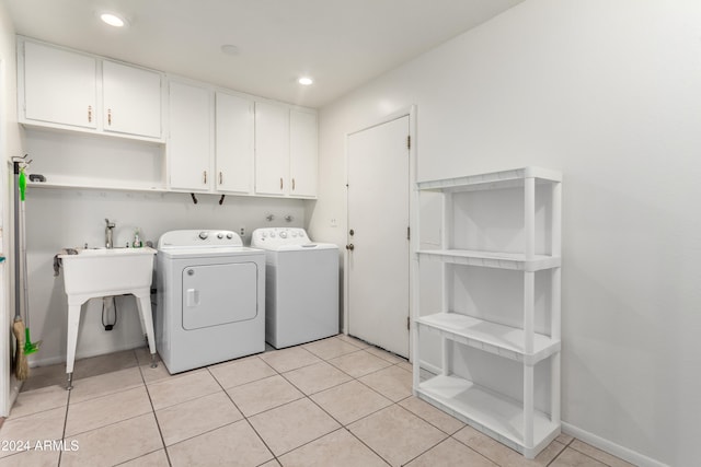 clothes washing area featuring light tile patterned flooring, cabinets, and washing machine and clothes dryer