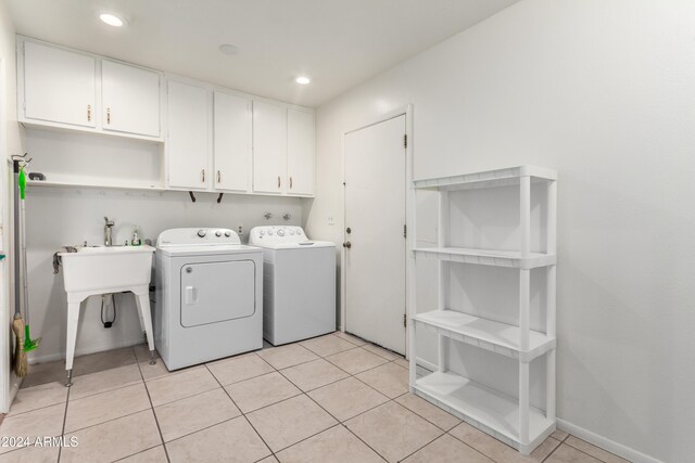 clothes washing area with cabinets, light tile patterned floors, and washer and clothes dryer