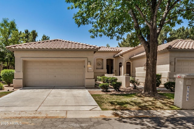mediterranean / spanish home featuring concrete driveway, stucco siding, a tiled roof, and an attached garage