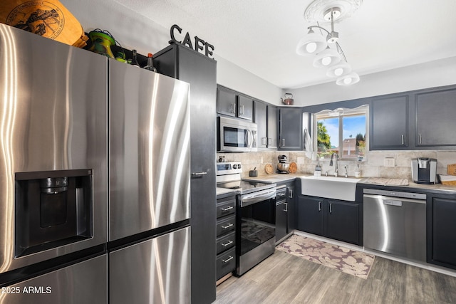 kitchen featuring sink, light hardwood / wood-style floors, tasteful backsplash, and appliances with stainless steel finishes