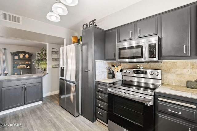 kitchen featuring appliances with stainless steel finishes, light hardwood / wood-style flooring, and tasteful backsplash