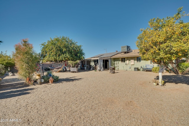 rear view of property featuring cooling unit and solar panels