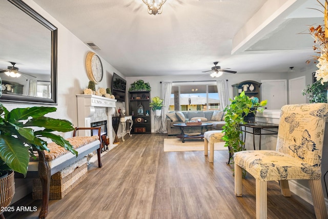 living room featuring hardwood / wood-style flooring, ceiling fan, and a tiled fireplace