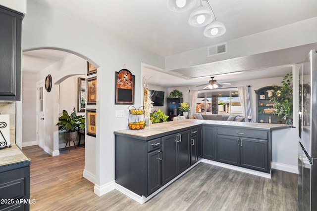 kitchen with ceiling fan, dark hardwood / wood-style floors, gray cabinets, and kitchen peninsula