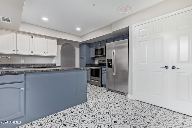 kitchen with blue cabinets, sink, white cabinets, and appliances with stainless steel finishes