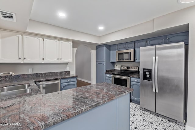 kitchen featuring kitchen peninsula, appliances with stainless steel finishes, blue cabinetry, and sink