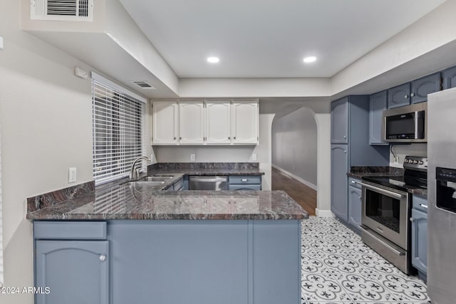 kitchen with blue cabinetry, sink, kitchen peninsula, white cabinets, and appliances with stainless steel finishes