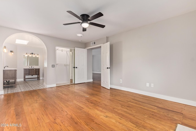 unfurnished bedroom featuring a spacious closet, a closet, light hardwood / wood-style flooring, and ceiling fan