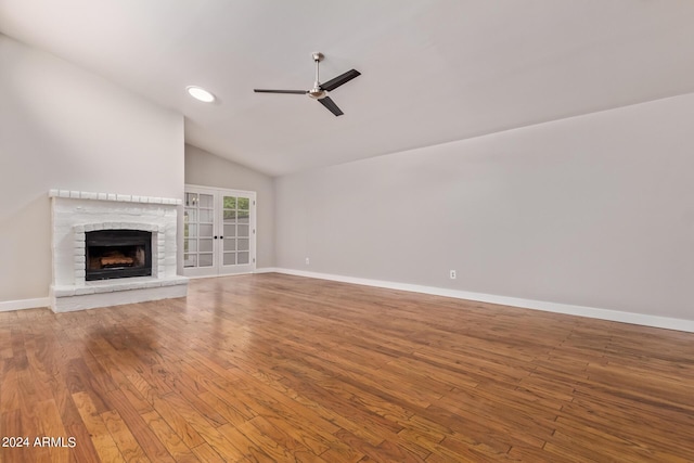 unfurnished living room featuring french doors, vaulted ceiling, ceiling fan, hardwood / wood-style flooring, and a fireplace