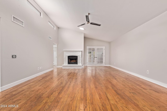 unfurnished living room featuring french doors, a brick fireplace, ceiling fan, high vaulted ceiling, and hardwood / wood-style floors