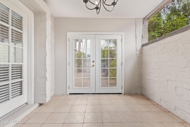 doorway to outside with a notable chandelier, light tile patterned floors, and french doors