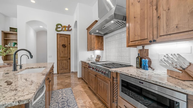 7130 E Saddleback St Unit 58, Mesa, AZ 85207 - kitchen featuring wall chimney exhaust hood, a sink, arched walkways, appliances with stainless steel finishes, and decorative backsplash