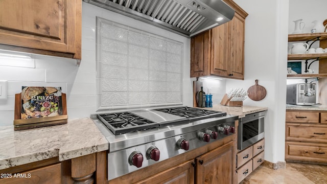 7130 E Saddleback St Unit 58, Mesa, AZ 85207 - kitchen featuring stainless steel appliances, premium range hood, decorative backsplash, brown cabinets, and light stone countertops