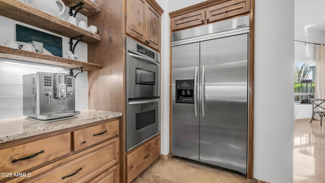 7130 E Saddleback St Unit 58, Mesa, AZ 85207 - kitchen with appliances with stainless steel finishes, open shelves, light stone countertops, and brown cabinetry