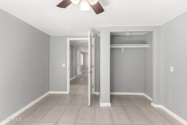 unfurnished bedroom featuring ceiling fan, light tile patterned floors, a closet, and baseboards