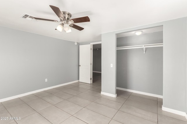 unfurnished bedroom with light tile patterned floors, a closet, a ceiling fan, and baseboards