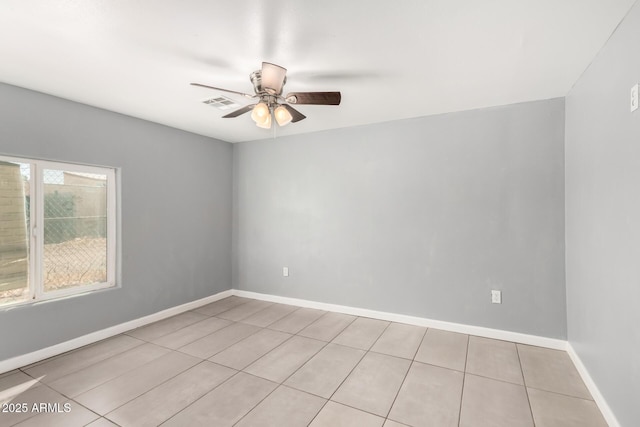 tiled spare room featuring visible vents, a ceiling fan, and baseboards