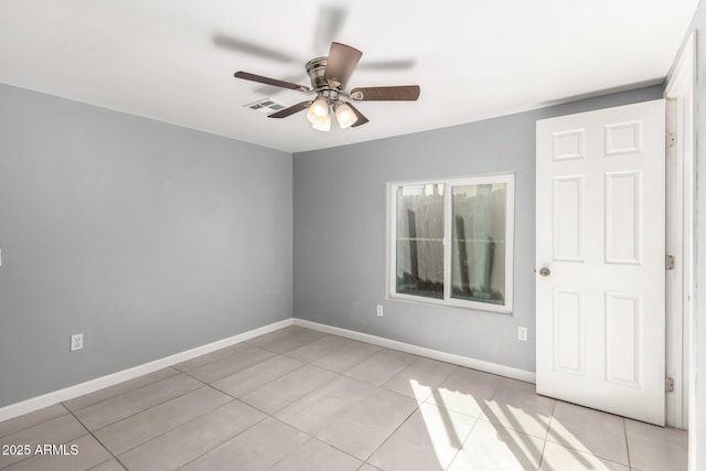 spare room with light tile patterned floors, ceiling fan, visible vents, and baseboards