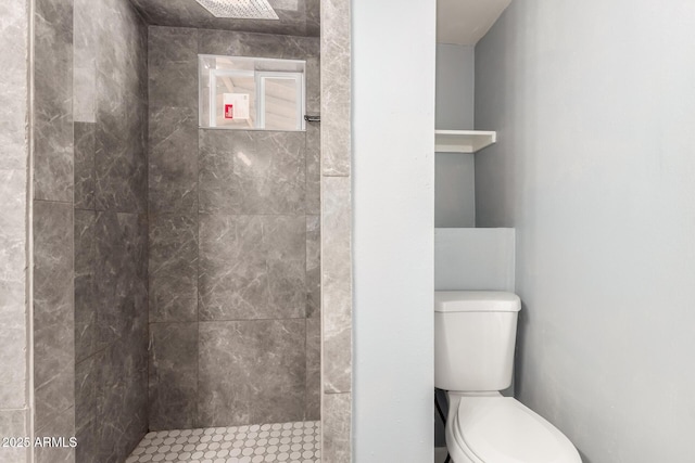 bathroom featuring tiled shower and toilet